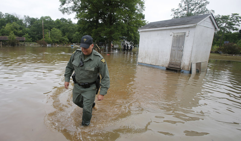 West Virginia State Trooper C.S. Hartman walks from a shed that he checked out as he and other crews search homes on Saturday in Rainelle, W.Va. by Steve Helber via AP 6-26-2016