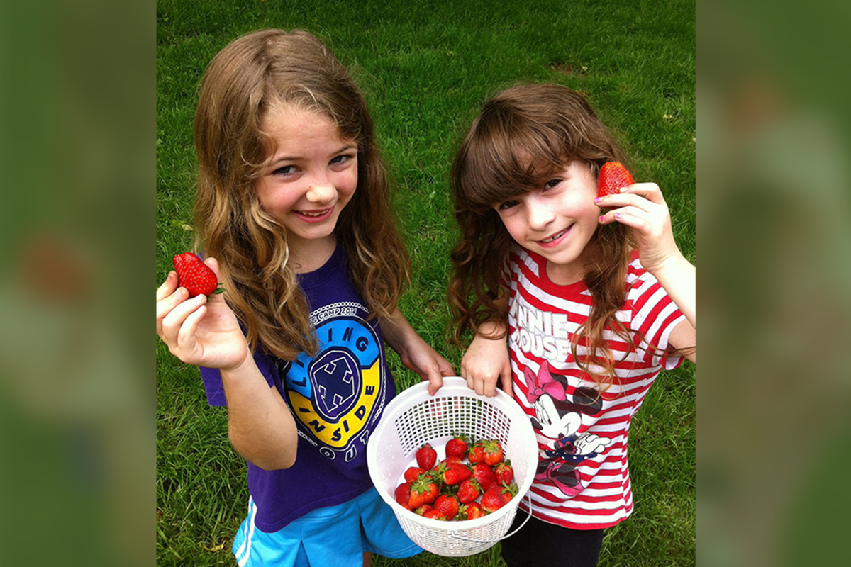 Eli McFarland, left, and Audree Born hold up fresh strawberries they picked at Country Road House and Berries during berry season.