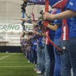 High school and middle school students toe the line to release arrows inside Marshall's indoor practice facility in Huntington